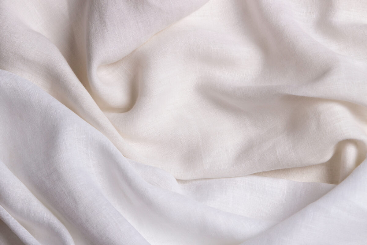 White crumpled linen fabric texture background. Natural linen organic eco textiles canvas background. Two shades of white color linen cloth material. Top view