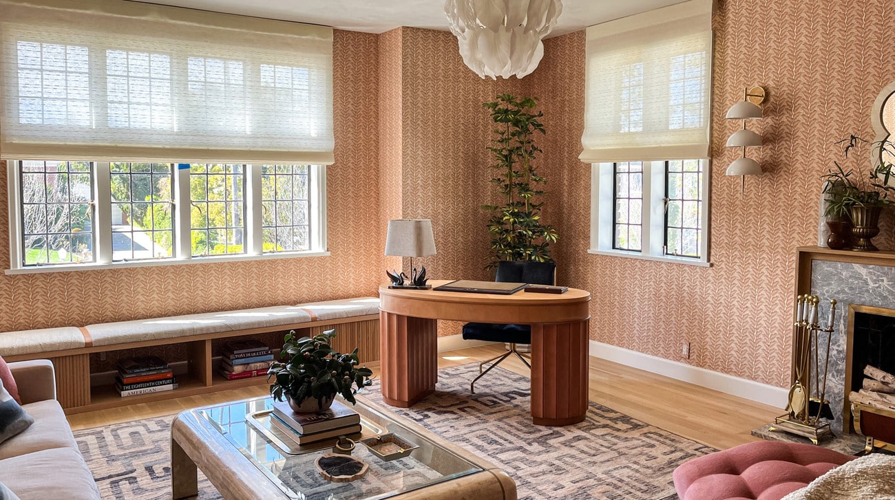 Windows with roman shades in a wallpapered room